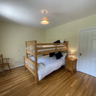 Redory House - Spacious family room with bunk bed sleeps 3 Bedside cabinet with lamp and chair at bottom of bed against the wall.